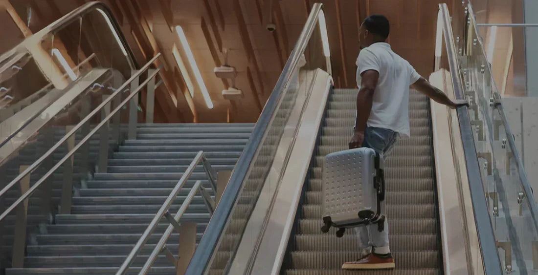 Mann mit Koffer von Hero auf einer Rolltreppe