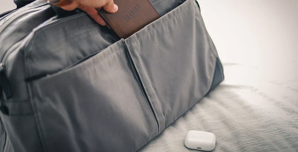 Graue Reisetasche, Kopfhörer und Geldbeutel