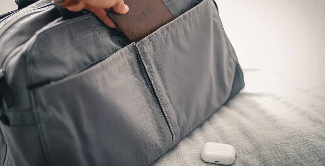 Graue Reisetasche, Kopfhörer und Geldbeutel