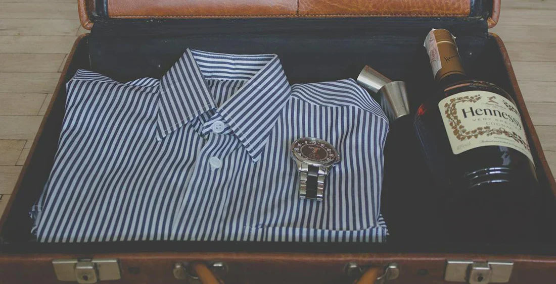 Koffer in dem ein Hemd, eine Uhr und eine Flasche sind