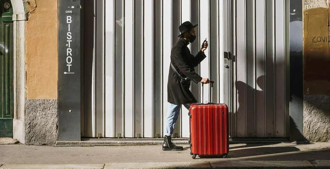 Person mit mittelgroßem, rotem Koffer