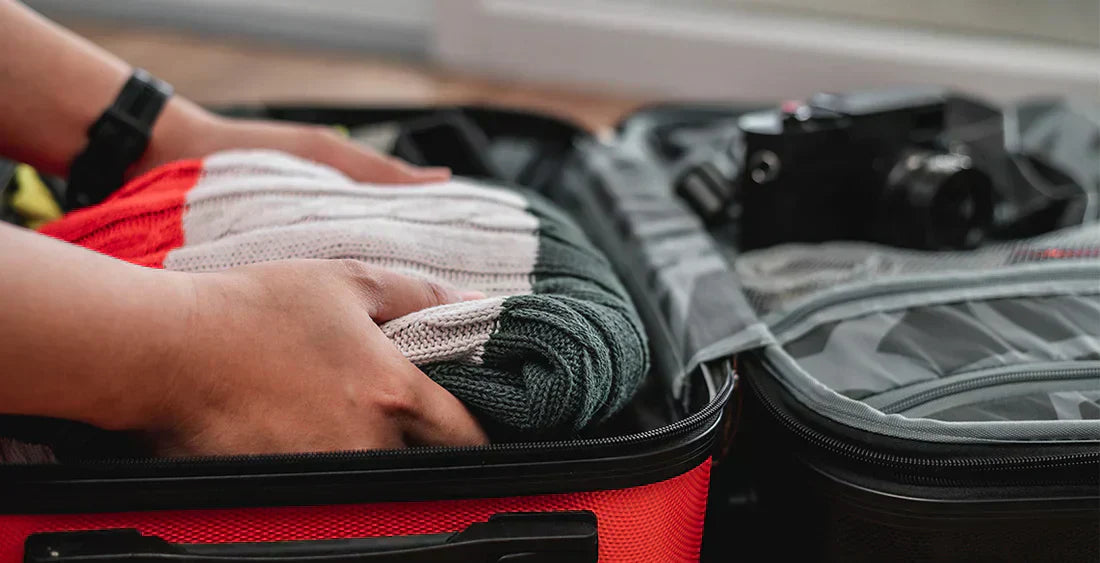 Person, die Kleidung in einen Koffer packt