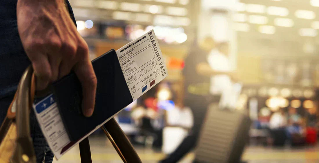 Person am Flughafen, die ein Reisedokument hält