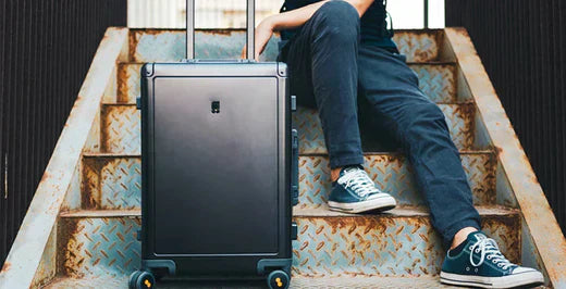 Mann mit Koffer ohne Reißverschluss sitzt auf einer Treppe