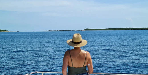 Frau im Badeanzug mit Hut vor dem Wasser